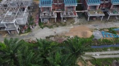 İkametgah evlerinin etrafında uçan bir erkek modelin havadan çekilmiş görüntüleri. İnşaat halindeki küçük boş arazisi var.. 