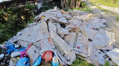 Perak, Malezya. 15 Eylül 2025: KgKoh çiftliğindeki izole hurdalıkta bulunan polipropilen tahıl çuvalları yığını.