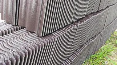 piles of new black rooftiles laying outside the construction site.