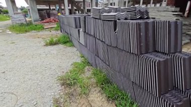piles of new black rooftiles laying outside the construction site.