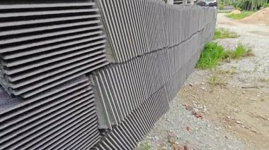 piles of new black rooftiles laying outside the construction site.