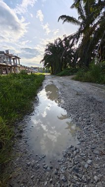 Kırsal toprak yolda sağanak yağış sonrasında durgun su havuzu yansıtıyor. 