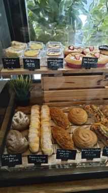Perak, Malaysia. September 18, 2025: Varieties of bread, pastry and cake on display and sale in the glass shelves at the Noah's Roastry cafe,Sitiawan.