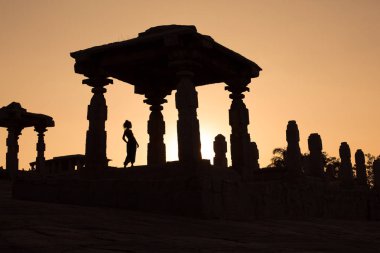 Silhouette bir kız Antik Hint Harabeleri ayarı kırmızı güneş zemin karşı duruyor