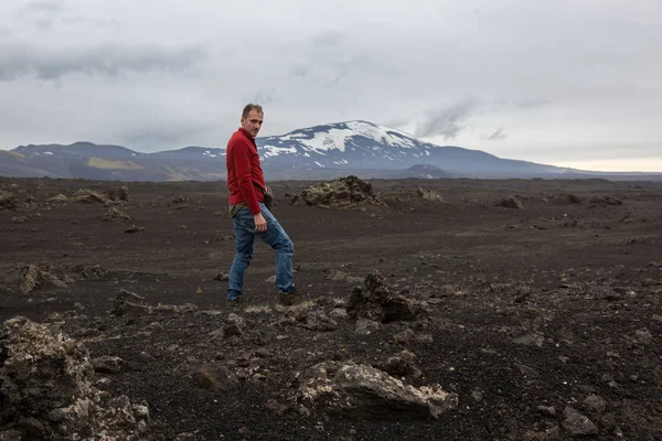 Uomo si erge su una pietra su un campo di lava bruciato — Foto Stock