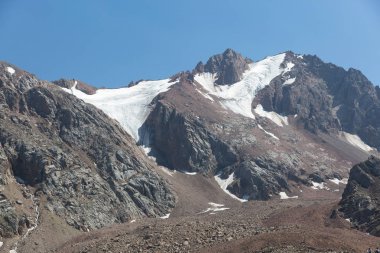 karla kaplı yüksek bir dağ taşı ve mavi bir gökyüzü