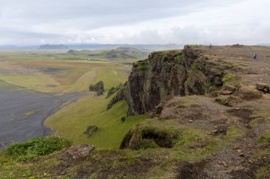 Ufka uzanan yeşil ovanın üzerindeki yüksek uçurum