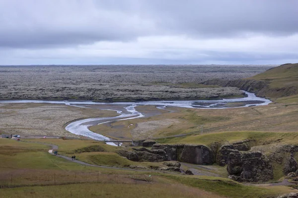 Diepe kloof, aan de onderkant van die stroomt een berg rivier en gaat in een lavaveld bedekt met mos — Stockfoto