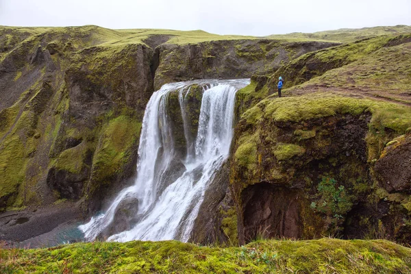 Het meisje staat aan de rand van de kloof bij de waterval Fagrifoss — Stockfoto