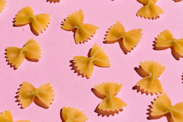 bow tie pasta isolated on pink background