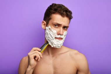 Hoşnutsuz bir ifadeyle genç ve harika bir adam, kameraya ciddi ciddi bakıyor.