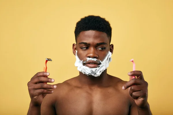 사려 깊은 남자는 두 개의 면도기를 들고 자신의 수염을 면도 그들 중 하나를 선택 — 스톡 사진