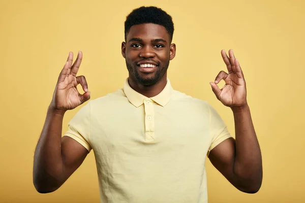 Positiv kille visar OK gest på en gul bakgrund. — Stockfoto