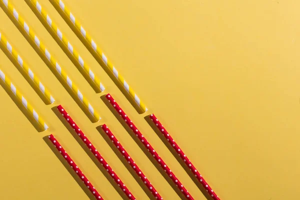Rote und gelbe Strohhalme isoliert auf gelbem Hintergrund — Stockfoto