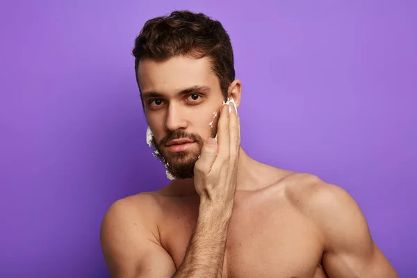 Уверенный в себе красивый мужчина трогает кожу лица во время утреннего бритья — стоковое фото