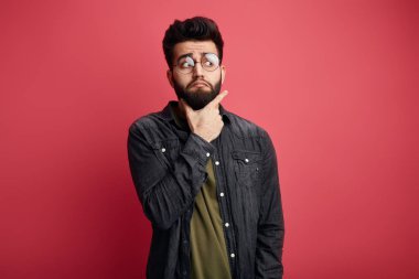 Ciddi çekici sakallı şık adam çene dokunmadan ve kamera bir kenara bakıyor