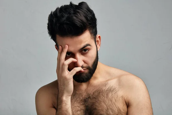 Handsome shirtless man covering face with palm