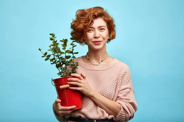 positive nice woman in fashionable clothes has grown the flower