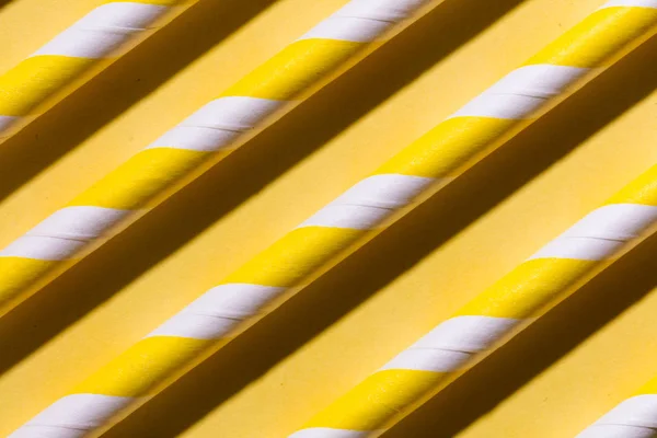 一排五颜六色的管子，条纹在平坦的黄色背景 — 图库照片