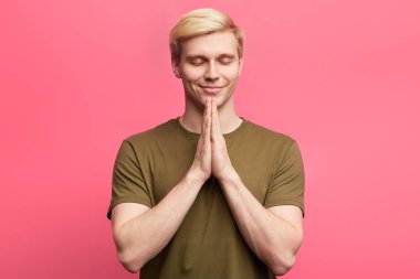 Genç sarışın adam dua ve meditasyonda el ele tutuşur.