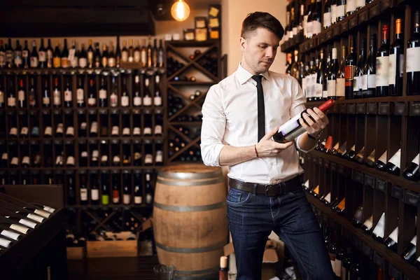 Atractivo sommelier con camisa blanca y pantalones de pie en la tienda de vinos — Foto de Stock