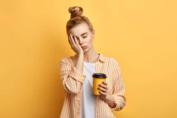 Müde blondhaarige schläfrige Frau hält eine Tasse Kaffee in der Hand — Stockfoto