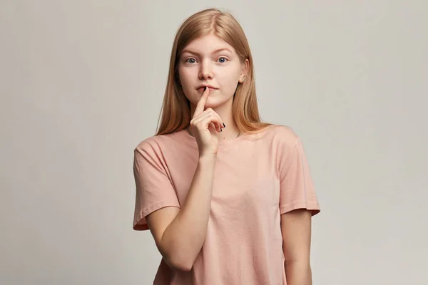 Emocjonalna piękna kobieta trzyma palec na ustach, pokazuje gest ciszy, — Zdjęcie stockowe