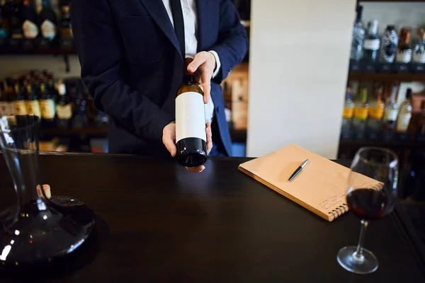 Hombres con ropa formal sosteniendo una botella de vino tinto en la tienda de vinos — Foto de Stock