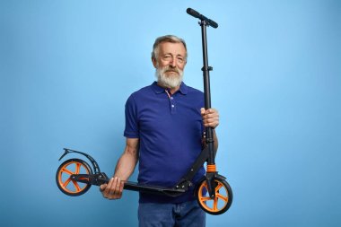 good looking mature man holding scooter and looking at the camera clipart
