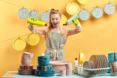 Genç, neşeli ev hanımı elinde iki şişe temiz sıvı tutuyor.