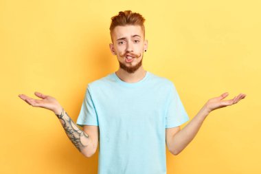 Tereddütünü ifade eden mavi tişörtlü şaşkın genç adam