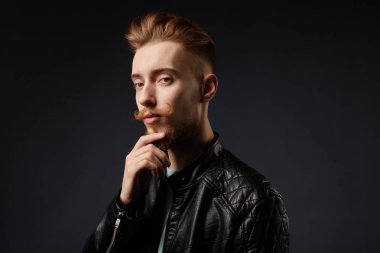 iyi görünümlü şık adam çenesini dokunmadan ve kameraya pensively bakıyor