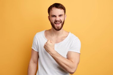 Zafer kutlayan beyaz t-shirt giyen neşeli heyecanlı mutlu adam