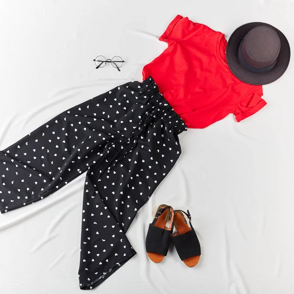 T-shirt elegante vermelho, calças pretas, sandálias, óculos no fundo branco — Fotografia de Stock