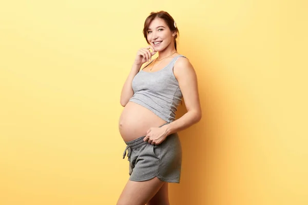 Menina feliz grávida com uma plam em seu queixo tocando sua barriga . — Fotografia de Stock