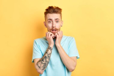 korkmuş duygusal genç adam kamera bakarak, çenesi altında avuç tutar