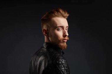 sıradışı bir görünüme sahip zencefil genç adam trendy deri ceket giyiyor