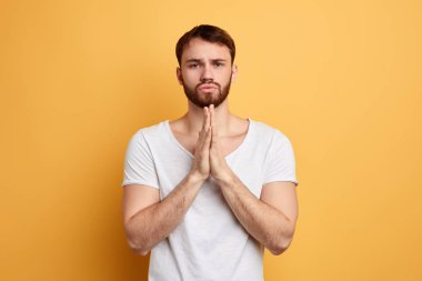 yalvarma ifade ile yakışıklı genç adam, avuç içi birlikte tutar