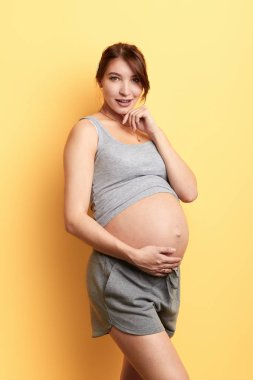 sarı duvar ile stüdyoda kameraya poz büyük göbek ile chraming kız