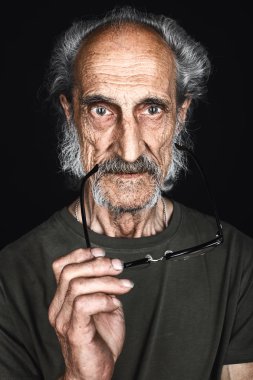 eski deneyimli yazar gözlük tutarak ve kamera bakıyor