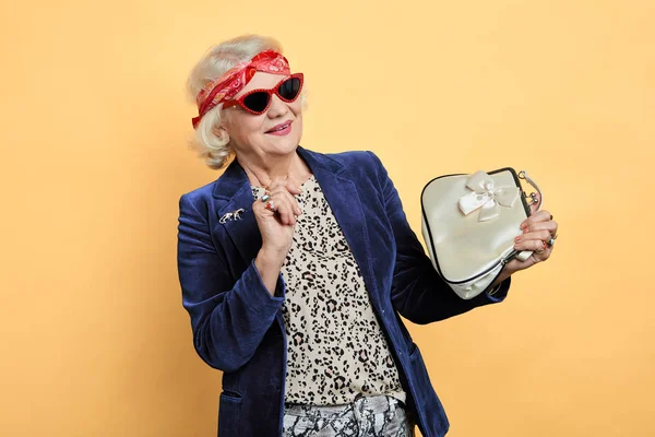 Блондинка крутая бабушка смотрит на свою новую белую сумку — стоковое фото