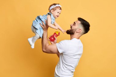mutlu baba elinde küçük çocuğu tutan sarı arka plan üzerinde izole
