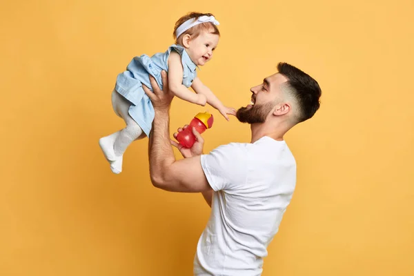 Lycklig Fader som håller sin lilla unge i händerna isolerade över gul bakgrund — Stockfoto