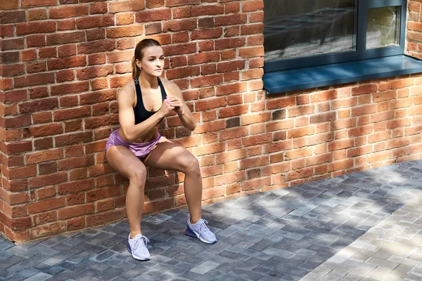 duvara yaslanmış iken çömelme yapıyor güçlü motive kız