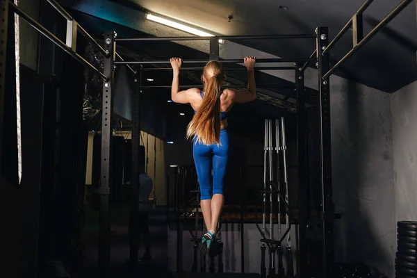 strong muscula girl with ponytail exercises pulling up