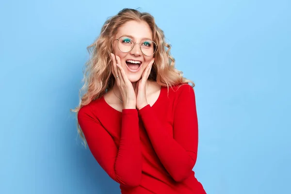 Positiva ragazza allegra con lunghi capelli biondi ondulati palme che tengono le guance — Foto Stock