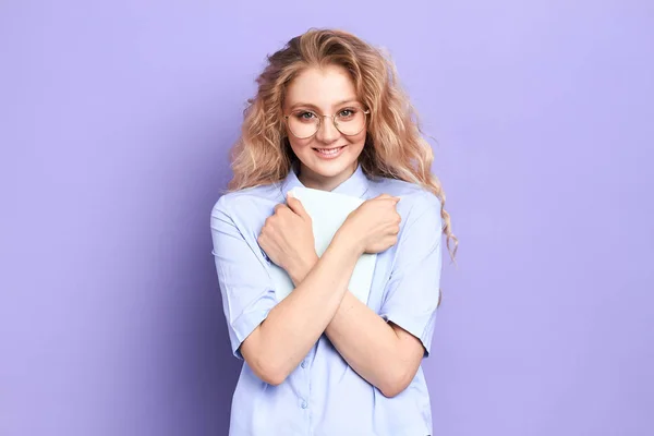 Felice donna positiva con lunghi capelli ricci ondulati in occhiali da vista abbracciare libro — Foto Stock