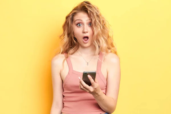 shocked young girl in pink top looking at mobile phone