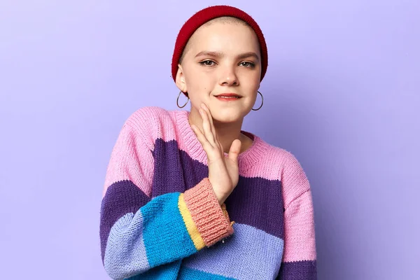 Young cool womanin knitted sweater and hat saying a secret hot braking news