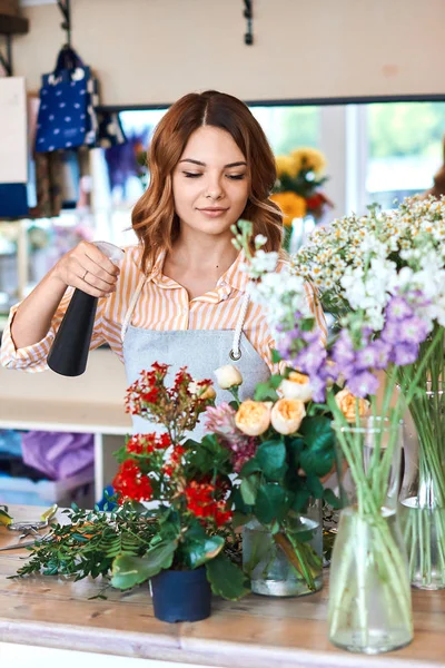 Impresionante mujer joven de buen aspecto rociando flores antes de venderlas — Foto de Stock